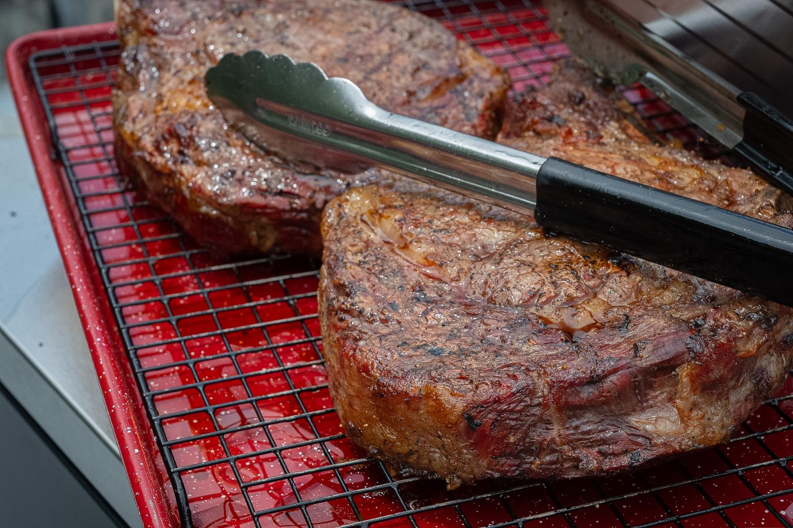 Grilled steaks resting with serving tongs
