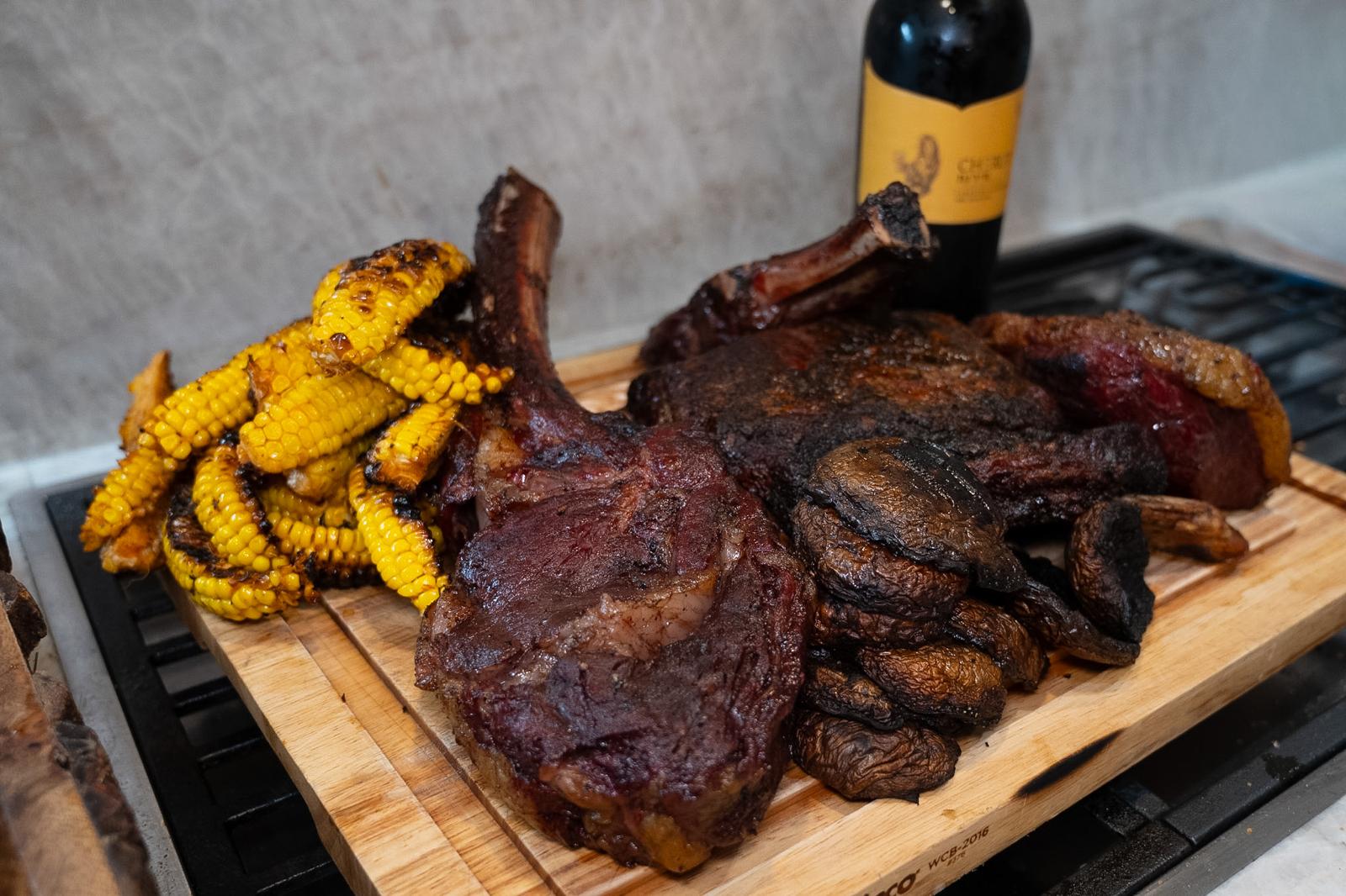 Grilled meat served with corn and mushrooms